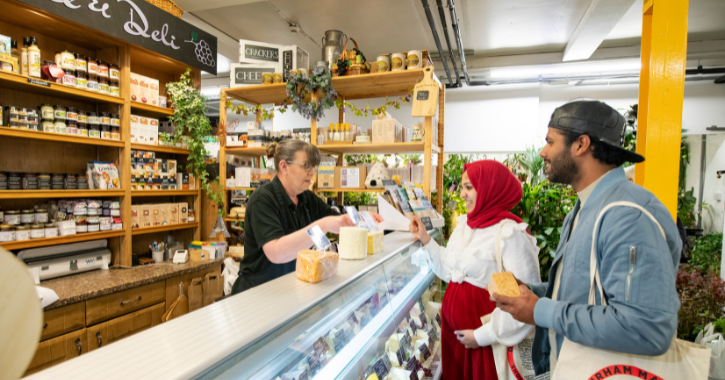man ands woman trying cheese from the deli counter inside Durham Market Hall.